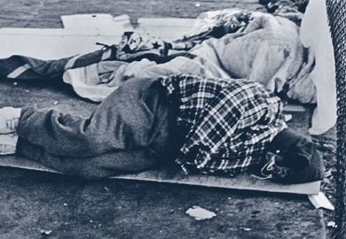 Homeless person asleep on street pavement