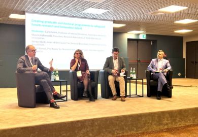 Four panelists sitting on couches on a stage in front of a screen at the THE Europe summit