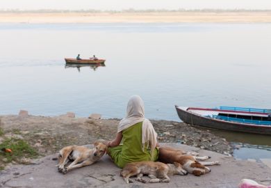 Scarfed young indian woman meditating on the border of the Ganges 
