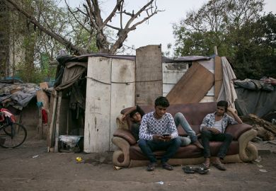 India young men sit on a sofa in a slum, illustrating graduate unemployment India young men sit on a sofa in a slum, illustrating graduate unemployment