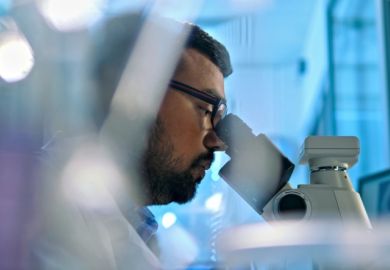 An Indian scientist looks through a microscope An Indian scientist looks through a microscope