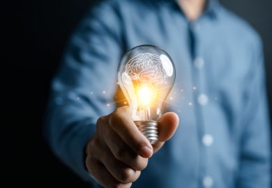 A man offers a lit lightbulb, signifying innovation
