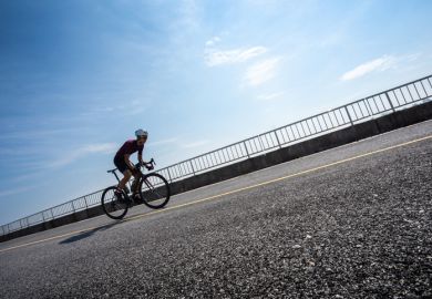 Cyclist cycling uphill on road