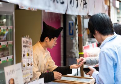 Tsukiji market street near Ginza with people paying coins cash for mochi.