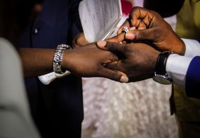 A groom puts a ring on his bride's finger