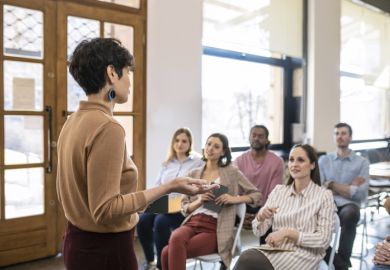 A woman giving a university lecture to several students 