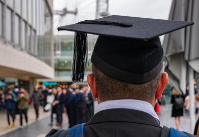  graduated student looking back to his colleagues and friends in University campus in London