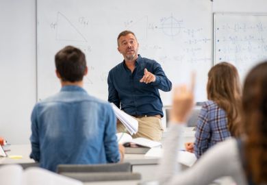 Professor pointing at college student with hand raised in classroom