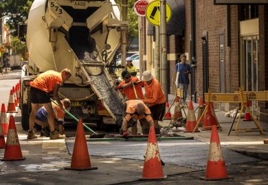 Group of men in orange dress pouring concrete from a truck