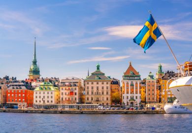 The Stockholm skyline with a flag of Sweden perched on a boat 