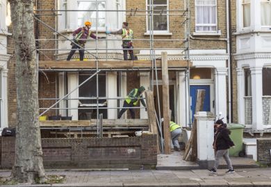 Four workers collaborate to build a scaffold during the refurbishment of a residential premises in London.