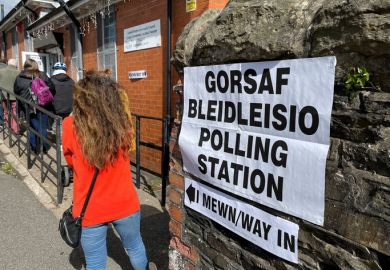 Queue of people waiting to enter a polling station in a village hall