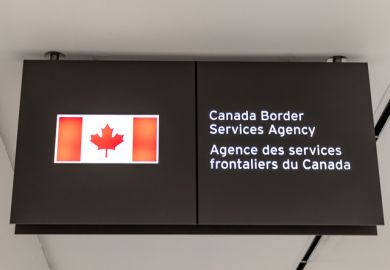 A Canadian flag next to a bilingual sign reading Canada Border Services Agency located in Terminal 3 of Toronto Pearson airport