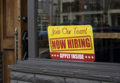 Now hiring sign is seen at the storefront of a local business