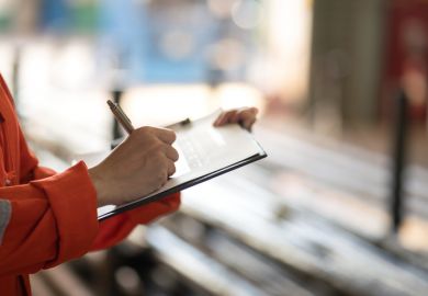 Writing on safety checklist document during safety audit and inspection.