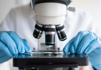 Researcher working with microscope wearing blue gloves Researcher working with microscope wearing blue gloves