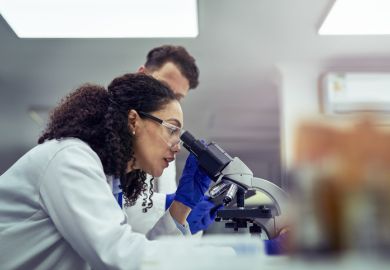 A woman looking at test sample through a microscope in laboratory