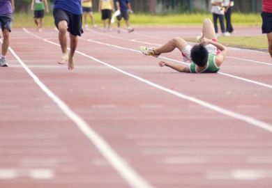 A runner falls over in a race on a track