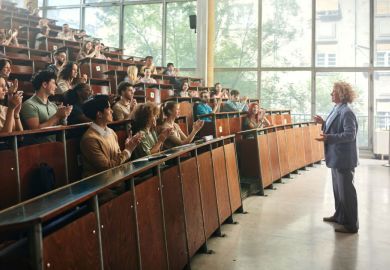 Dozens of students in a lecture hall applauding to their professor