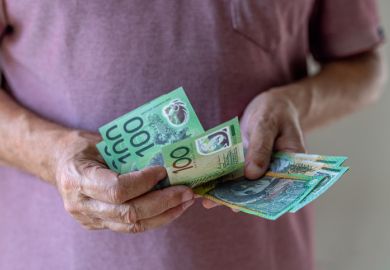 Close-up of a man counting a wad of 100 Australian dollar banknotes.