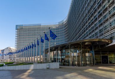 Entrance to the Berlaymont building, headquarters of the European Commission, with several EU flags lining the edge