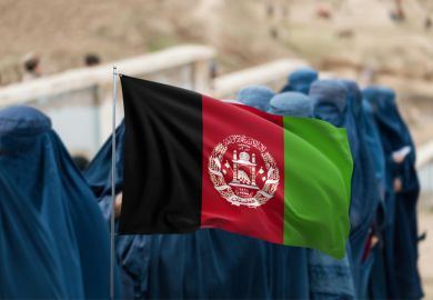 Afghan flag displayed over group of women wearing burqas 