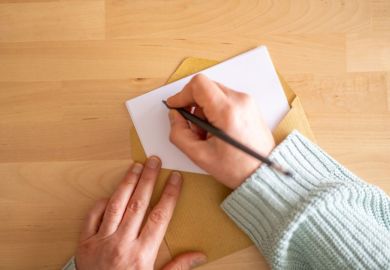 Person writing a letter on a blank sheet of paper