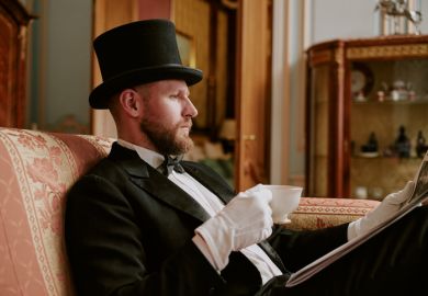 Man wearing formal suit and top hat sitting on sofa reading newspaper