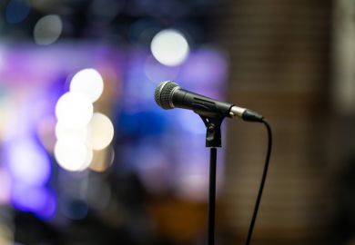 Close-up of a professional microphone on a stand with colorful stage lights blurred in the background