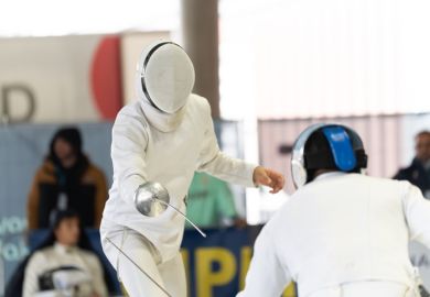 Fencers in protective gear competing