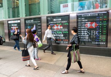 Pedestrians walk past a financial display board in Mong Kok, Kowloon, Hong Kong, China.