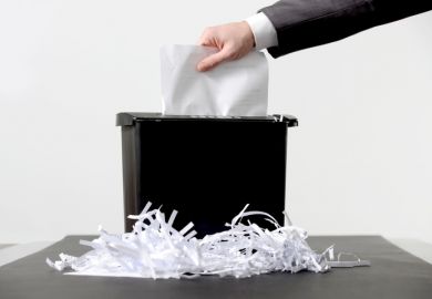 Hand of businessman putting a document in paper shredder