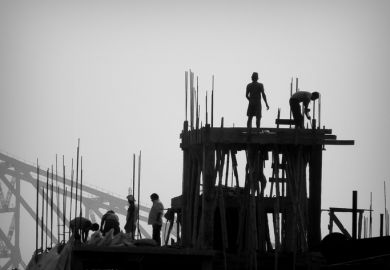  Construction workers and Engineers working for the construction of a high rise building in Kolkata with the famous Howrah Bridge in the background.
