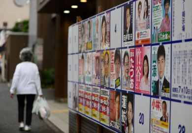 Woman walks past election posters