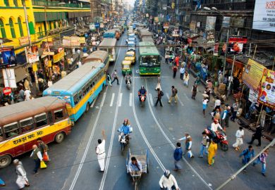 Pedestrians cross the road in front of motorcycles, cars and buses at the crossroads on January 20, 2013 in India.