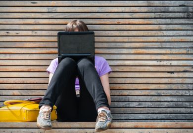 woman using a small black laptop on a bench