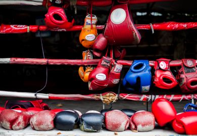 Boxing gloves hang off a boxing ring