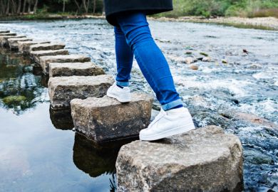 Person walks across stepping stones