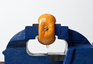 Orange being squeezed in a vice