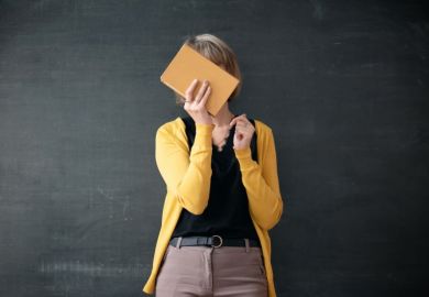Teacher hiding face with a book hiding face