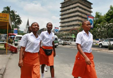 Girls walk along a street in Dar es Salaam, Tanzania Girls walk along a street in Dar es Salaam, Tanzania