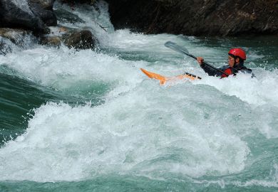 Person in a kayak paddling upstream. To illustrate that a one-off inflationary tuition fee rise will do little to help the financial instability of the higher education sector in England