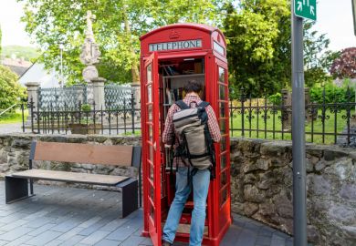 In Germany, a red telephone booth is used for the free exchange of books – a man is looking inside