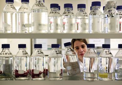 A female scientist looking at bottles of chemicals in a lab