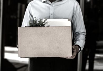 A man carries a box of his belongings, illustrating redundancy A man carries a box of his belongings, illustrating redundancy