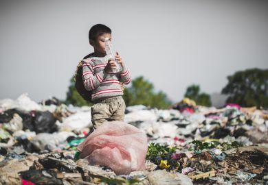 A poor boy finds a plastic bottle in a landfill site