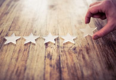 A hand lays out five plastic stars on a wooden surface Laying out stars