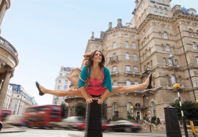A woman leapfrogs a bollard in London A woman leapfrogs a bollard in London