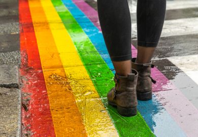 Feet walking on a rainbow road crossing