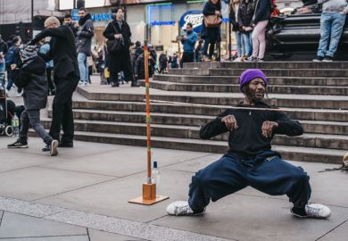 London, UK - November 24, 2019 Street performer limbo under the bar in Piccadilly Circus, one of the most popular tourist areas in London, UK, selective focus.